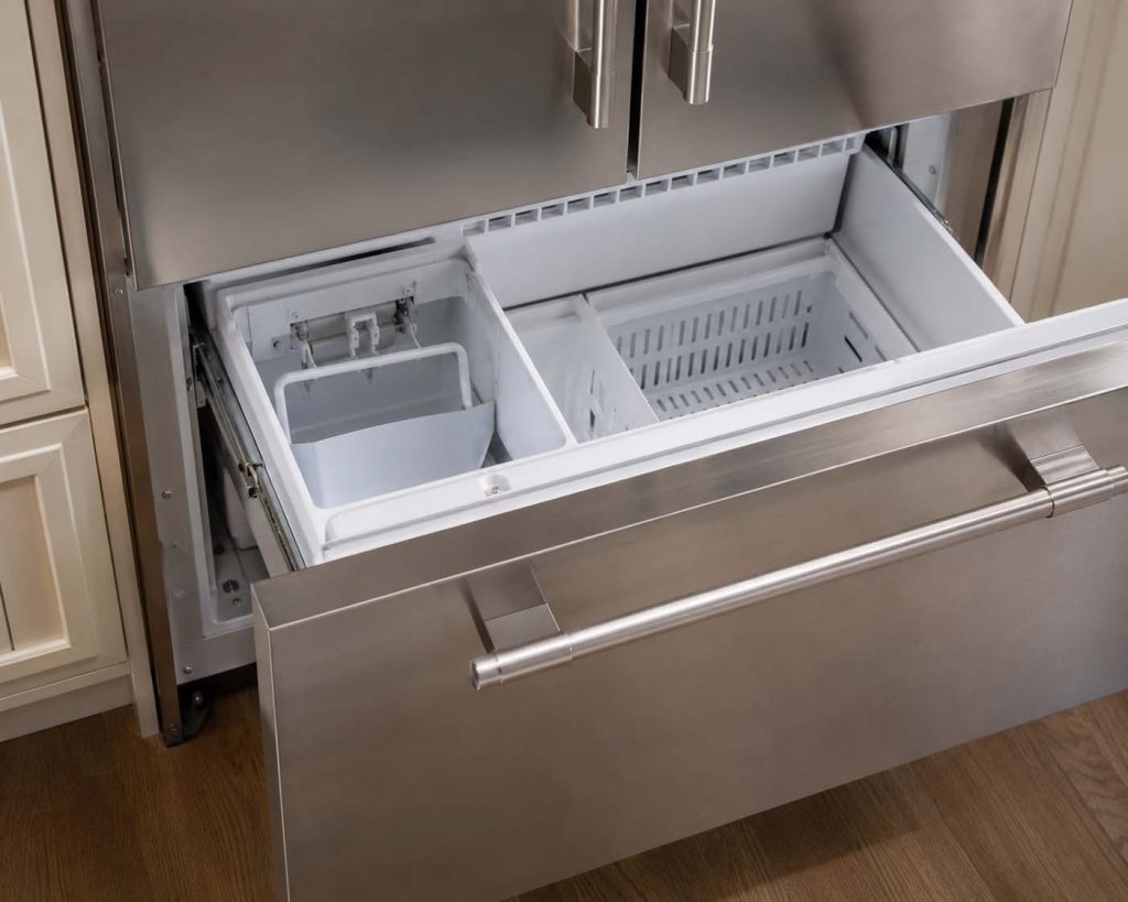 Sub-Zero built-in refrigerator with freezer drawer open showing an empty ice maker bin