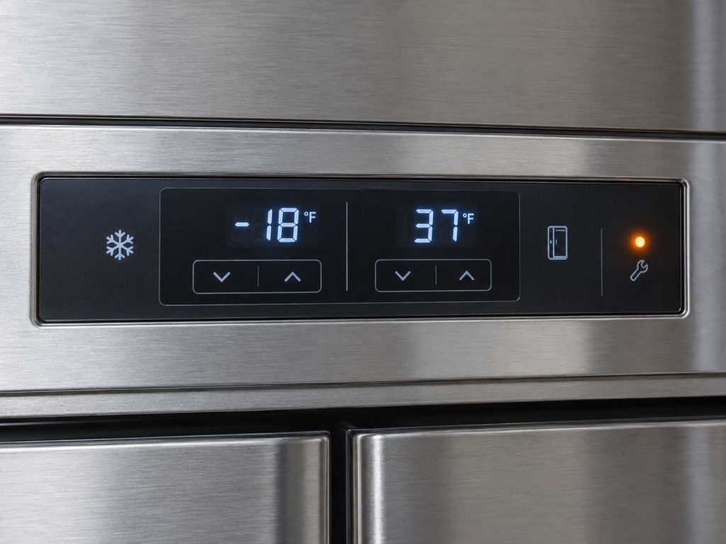Close-up of a Sub-Zero built-in refrigerator control panel with the temperature display and a lit service indicator