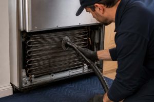 Technician cleaning condenser coils on a Sub-Zero refrigerator